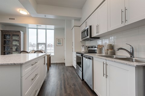 A kitchen with white cabinets and a wooden floor.