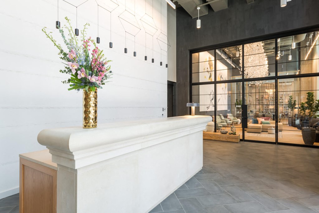 a lobby with a white counter and a vase with flowers