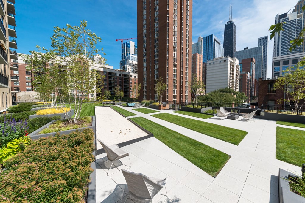 a park with grass and benches in a city with skyscrapers
