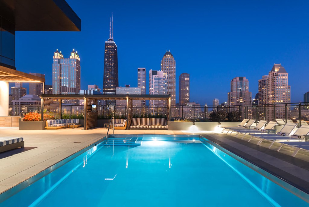 a pool on the roof of a building with the city skyline in the background