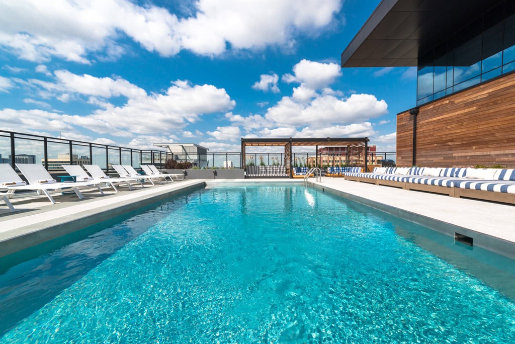 the pool on the rooftop of a building with white lounge chairs