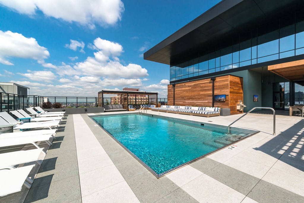a swimming pool on the rooftop of a building with lounge chairs