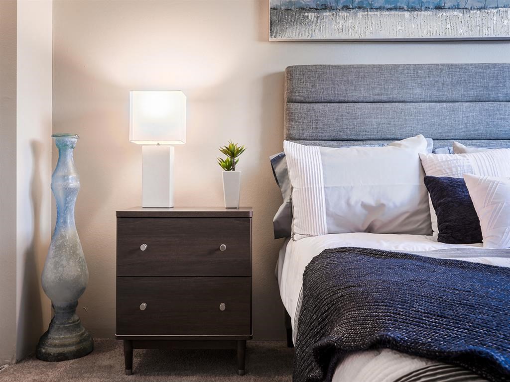 a bedroom with a bed and a night stand with a lamp