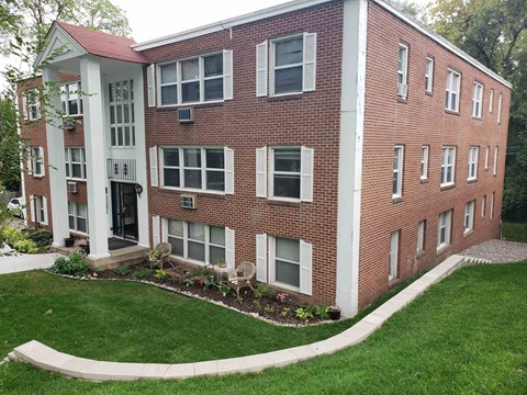 the front of a brick apartment building with green grass