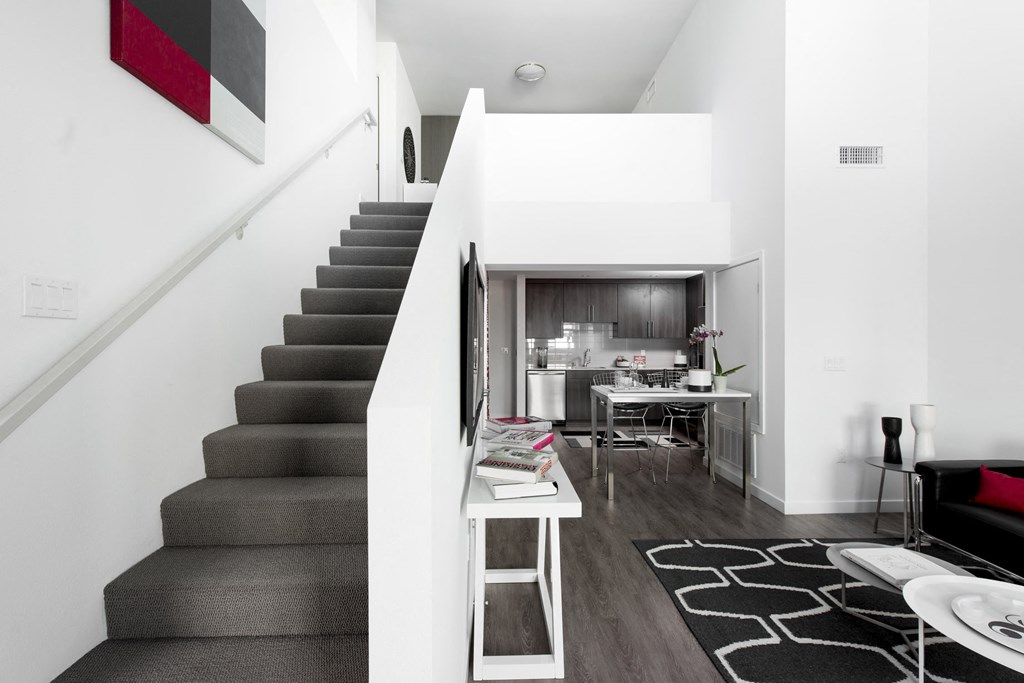 a living room with a staircase and a kitchen in the background