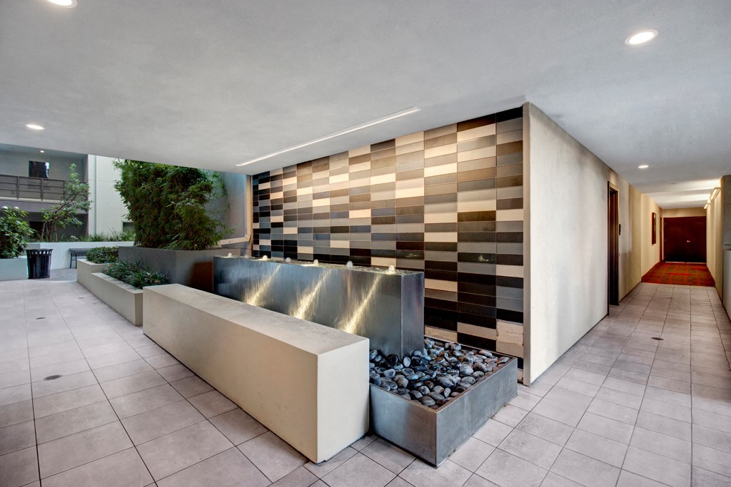 a lobby with a fountain and a tile wall