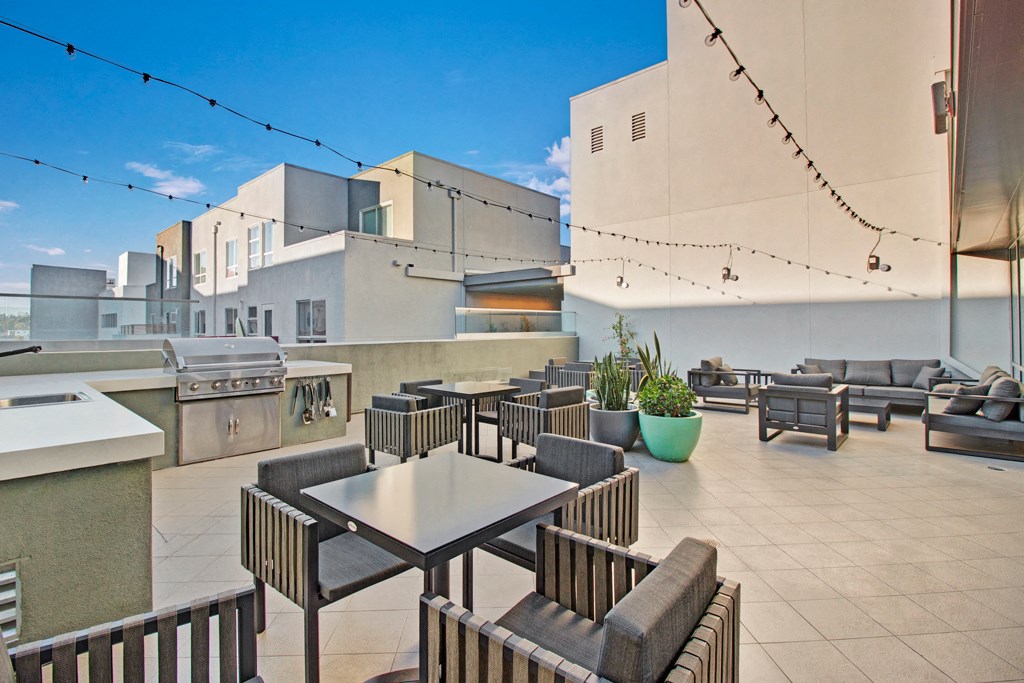 a rooftop patio with tables and chairs and a grill