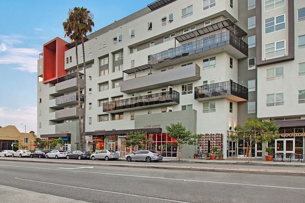 a city street with cars parked in front of an apartment building