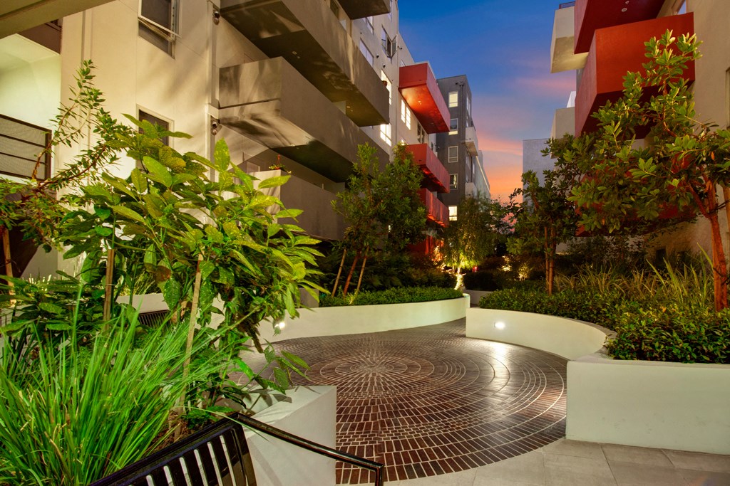 a courtyard between two buildings with trees and plants