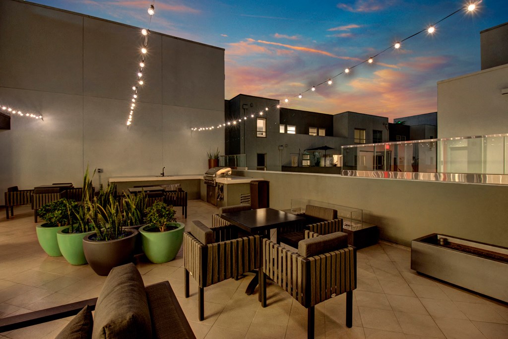 a rooftop patio with tables and chairs and a sunset in the sky