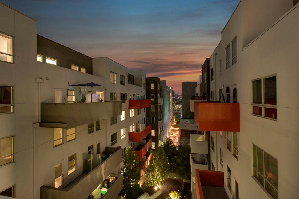 a rendering of a city street at night with buildings and a sunset