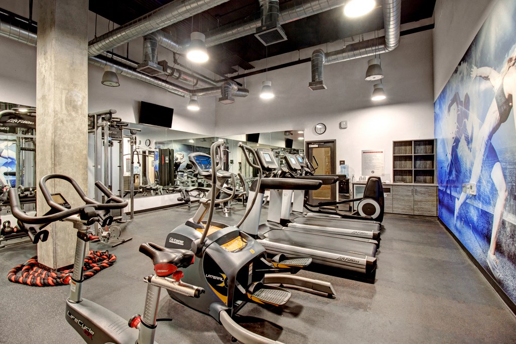 a gym with cardio equipment and weights on the floor