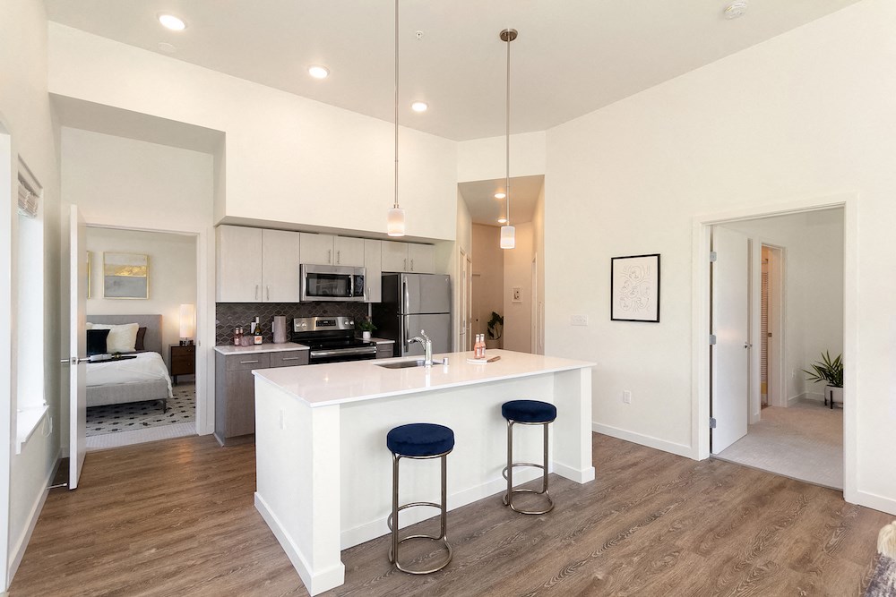 a kitchen with an island and stools in front of a living room