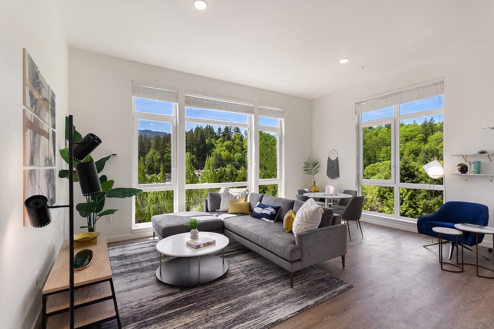 a living room with a couch and a table in front of large windows