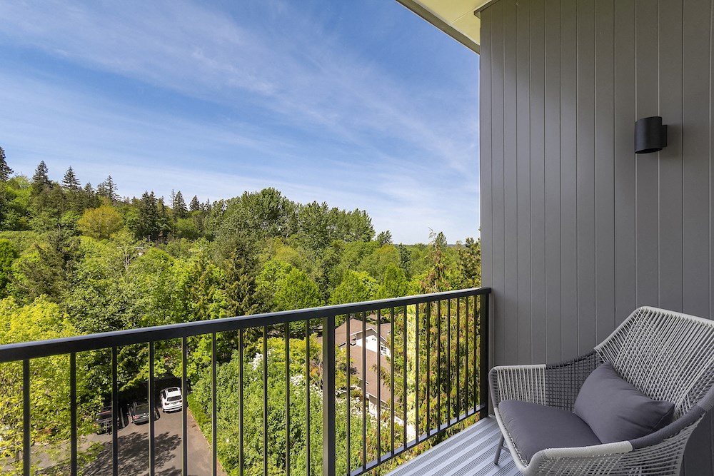a balcony with two chairs and a view of a forest