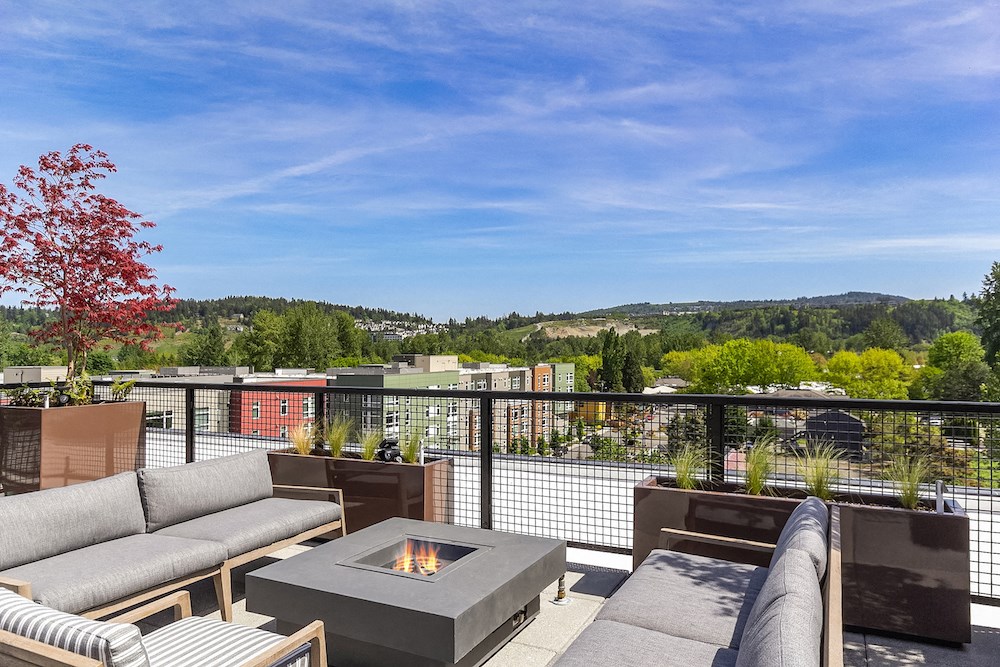 a rooftop deck with couches and a fire pit