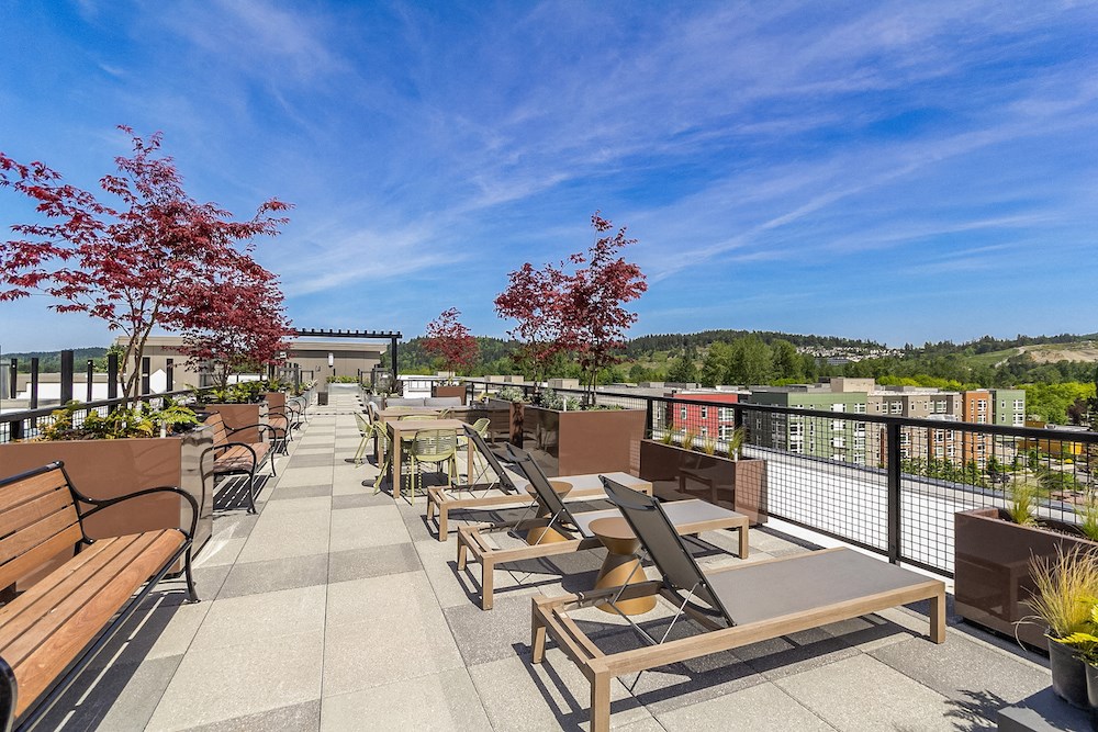 a rooftop patio with benches and tables on a sunny day