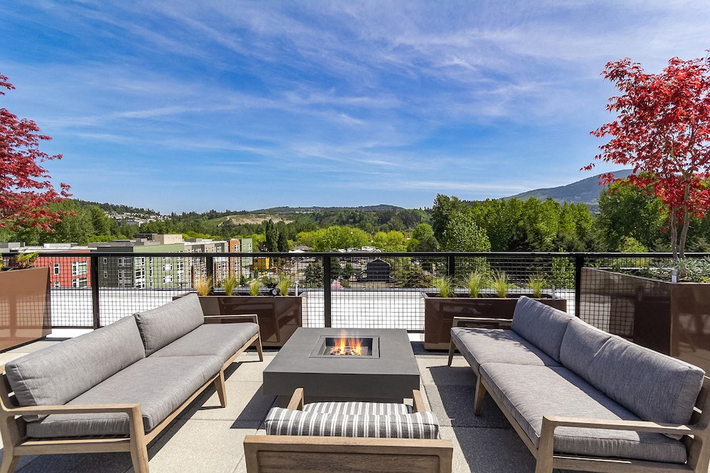 a rooftop deck with couches and a fire pit