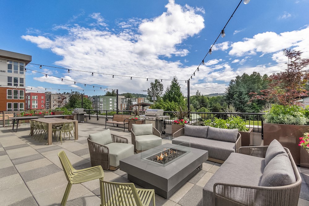 a rooftop patio with couches chairs and tables and a fire pit