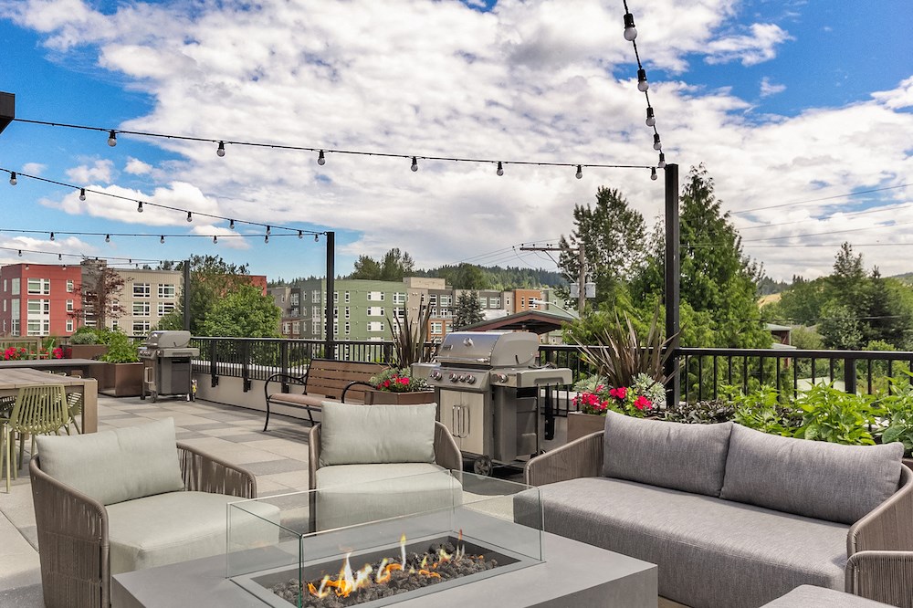 a rooftop patio with couches and chairs and a fire pit