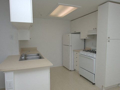 an empty kitchen with a sink and a refrigerator