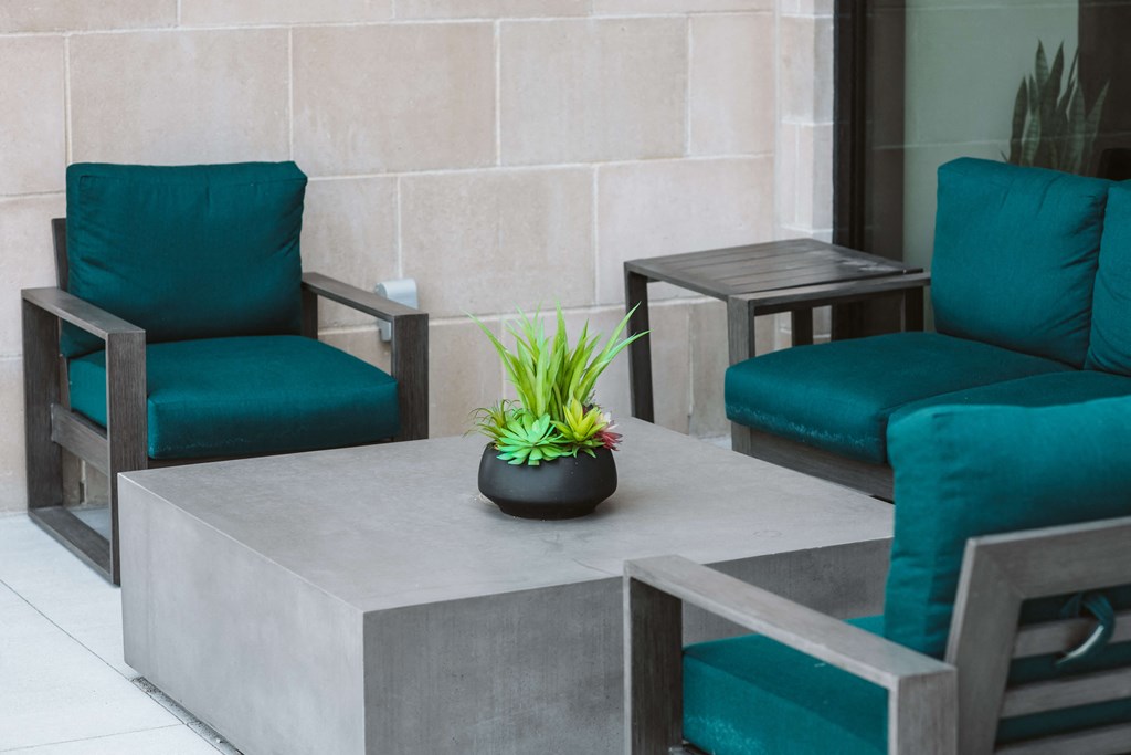 outdoor seating area with 3 blue lounge chairs around a square gray table at The Apex at CityPlace, Overland Park