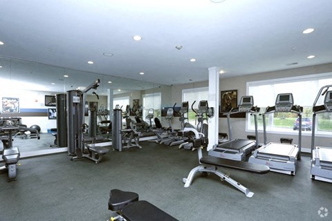 A gym with a variety of equipment including treadmills, weights, and exercise machines.