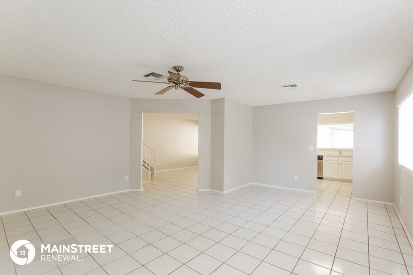 an empty living room with a ceiling fan and a tiled floor