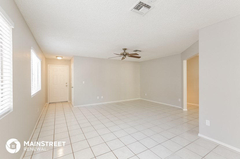 a spacious living room with tile flooring and a ceiling fan