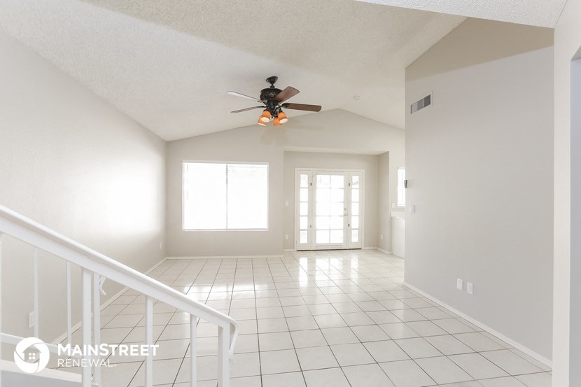 an empty living room with a ceiling fan and a staircase