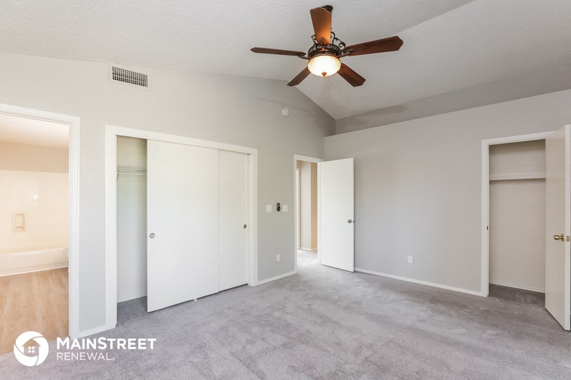 a living room with white walls and a ceiling fan