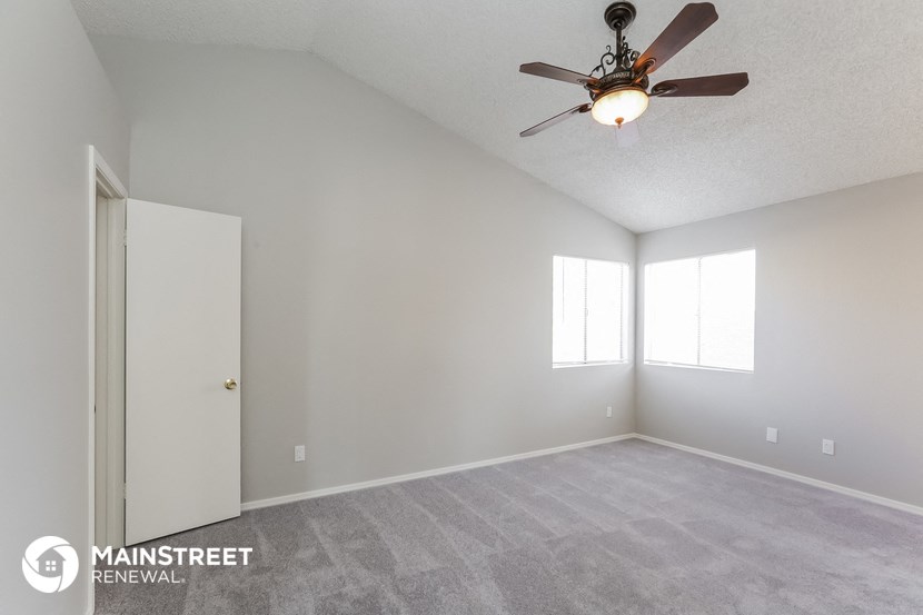 the spacious living room with ceiling fan and carpeting