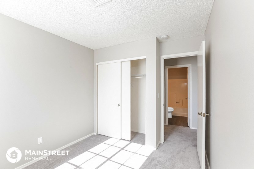 a master bathroom with a tiled floor and white walls and doors to a closet