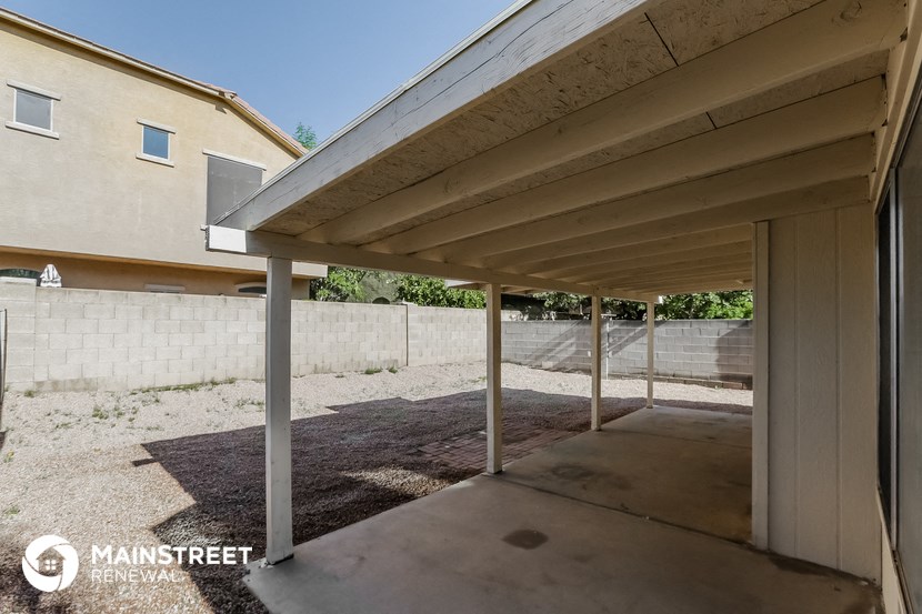 a covered patio with a wall in the background of a house