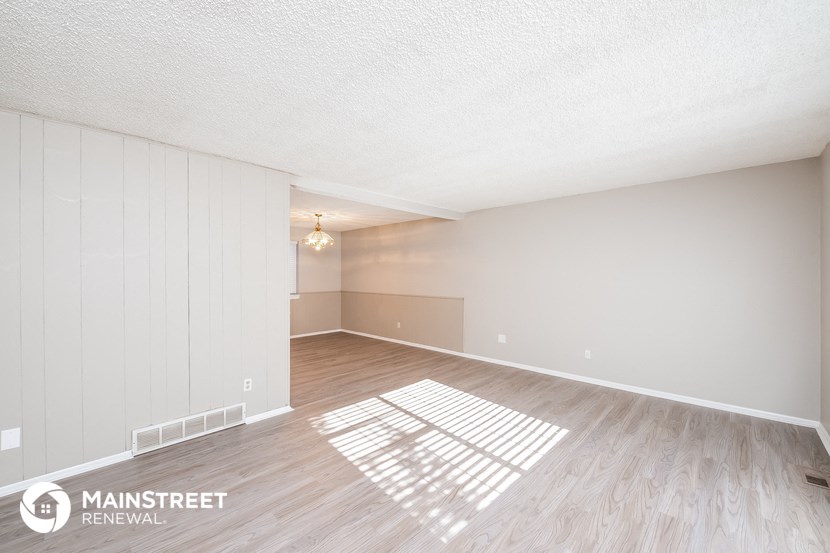 the spacious living room with wood flooring and white walls