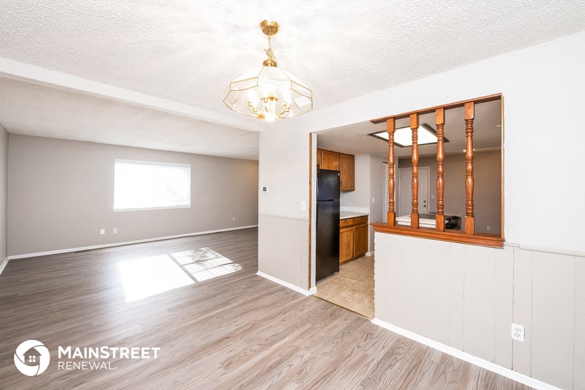 the kitchen and dining room of a white house with wood flooring