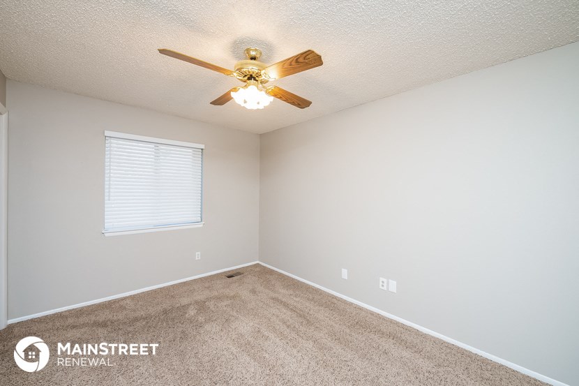 the spacious bedroom has carpet and a ceiling fan