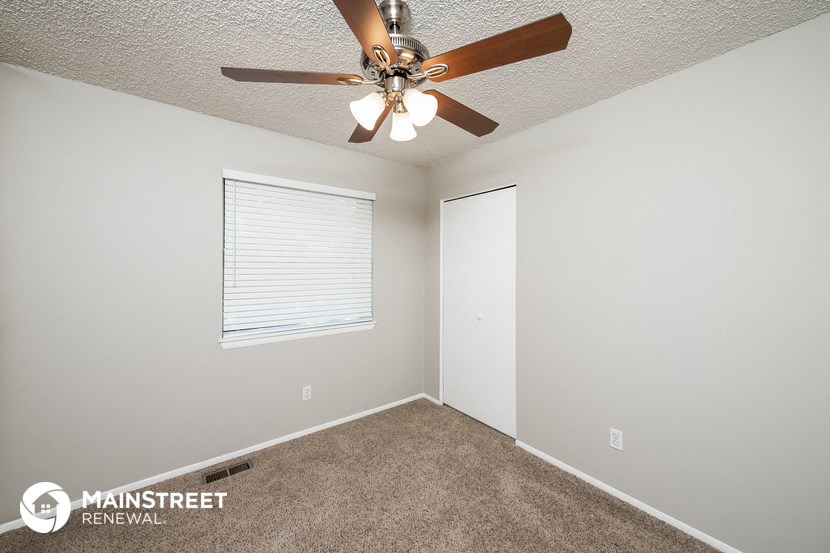 the interior of a bedroom with a ceiling fan and a window