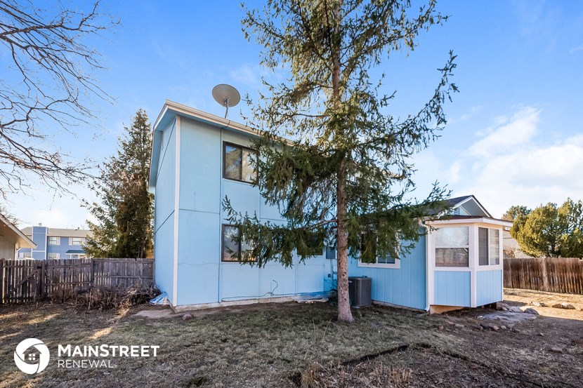 a small blue house with a tree in front of it
