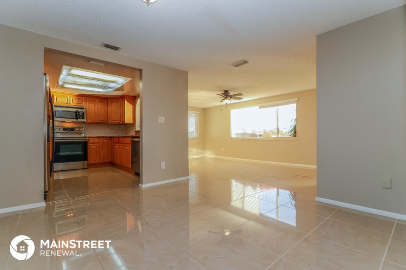 an empty kitchen and living room with tile floors and a ceiling fan