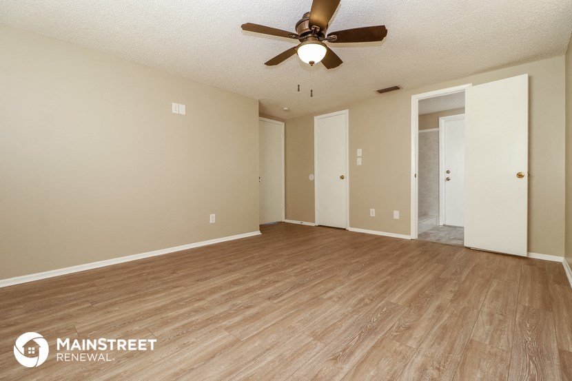 an empty living room with a ceiling fan and wood floors