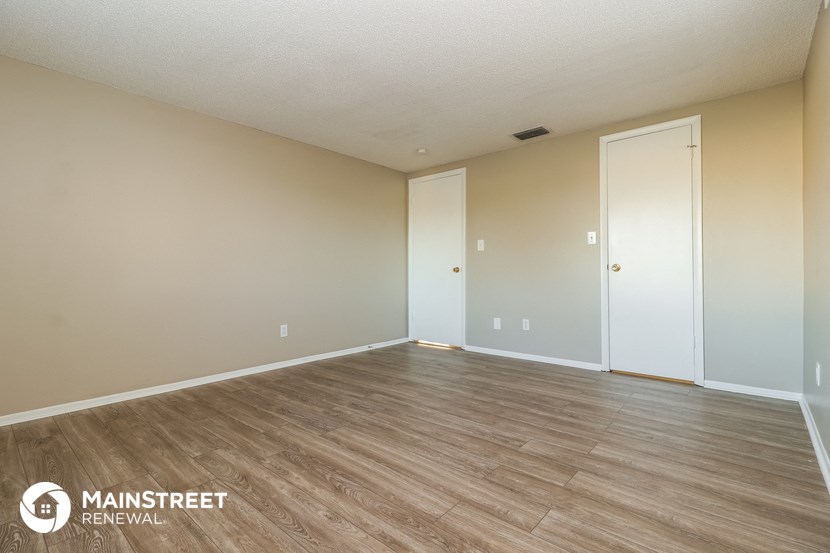 the spacious living room with wood flooring and white walls