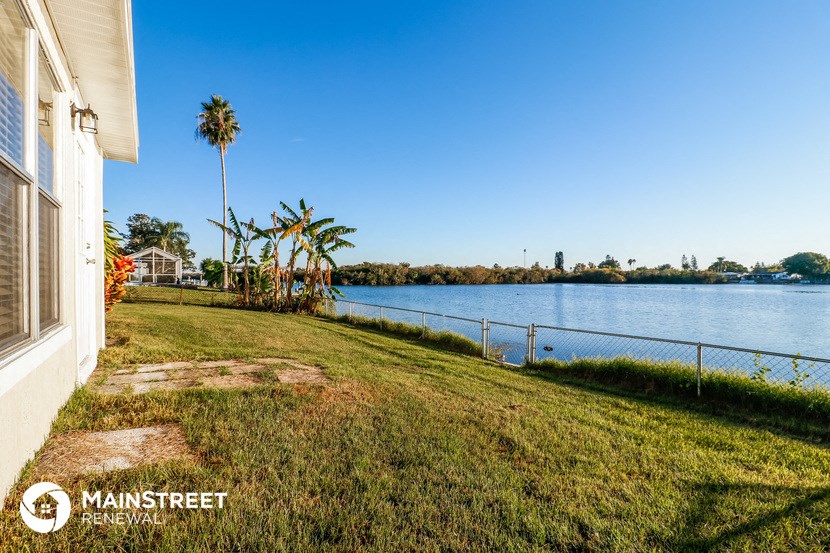 a view of the water from the side of a house with a grassy lawn