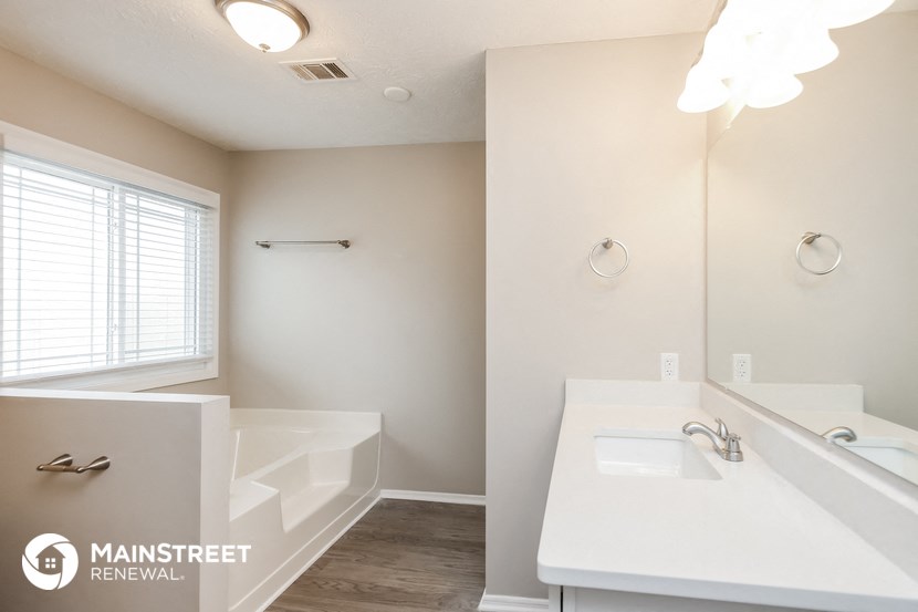 the master bathroom has a large mirror and a tub and sink