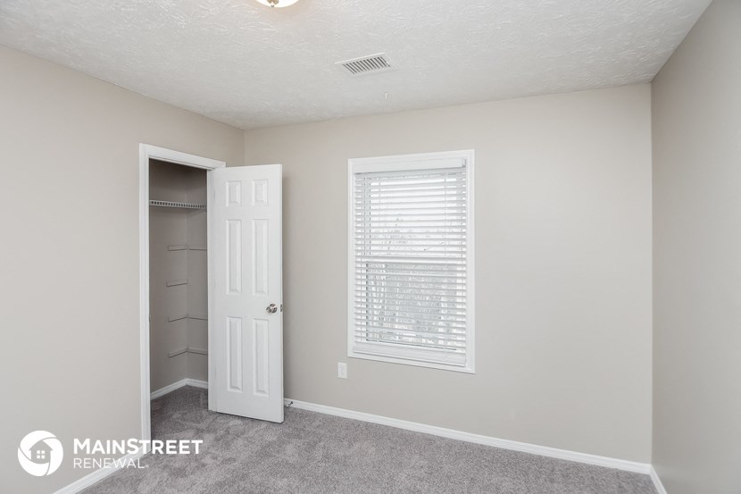 a bedroom with a closet and a white door and a window