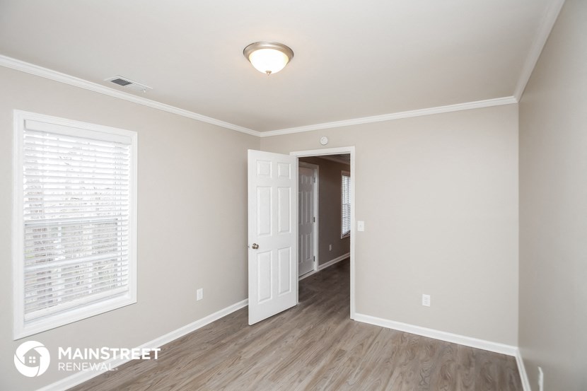 the living room of a new home with wood flooring and a white door