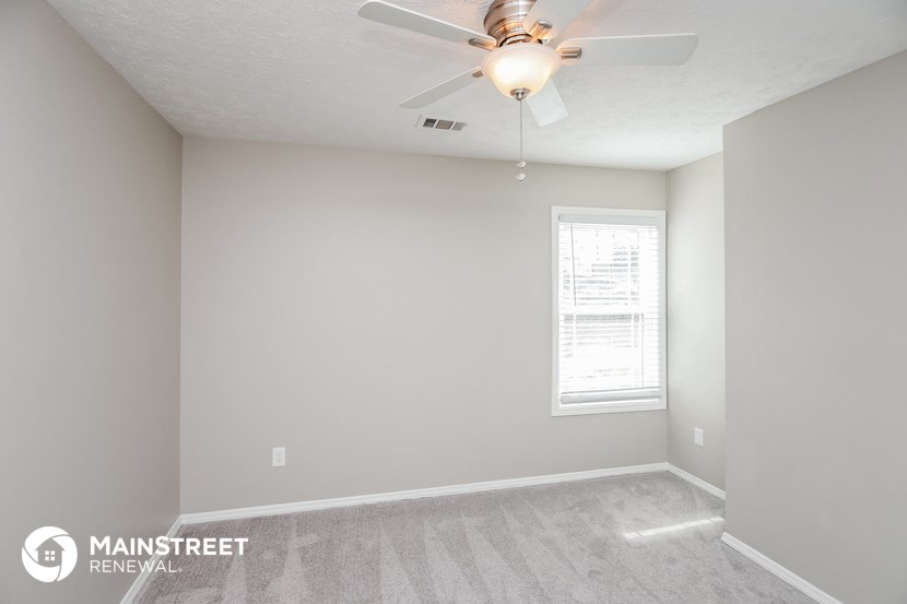an empty room with a ceiling fan and a window