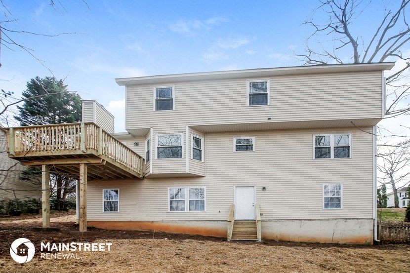 the back of a white house with a porch and a deck