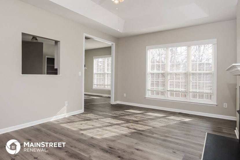 the living room of a new home with wood flooring and a large window