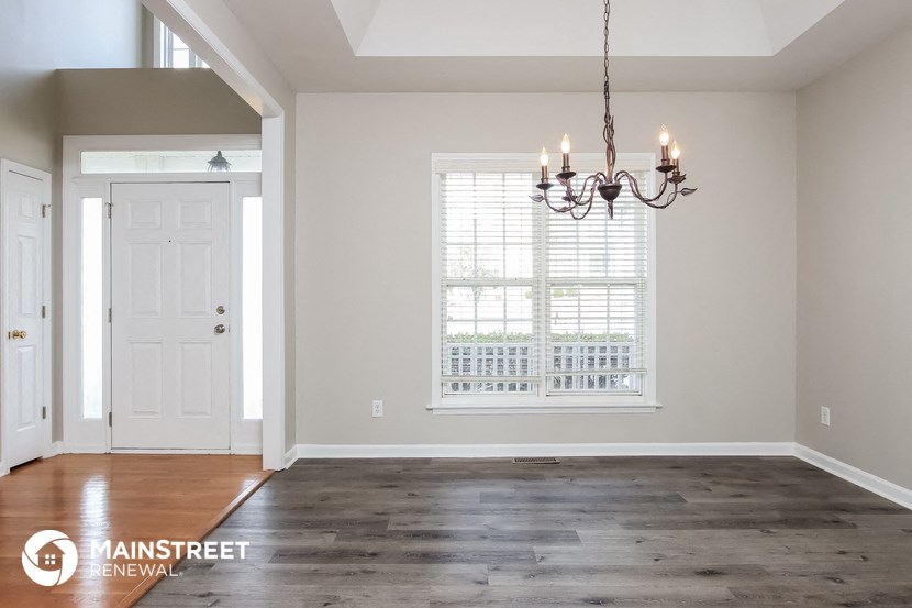 the living room of a home with a large window and a chandelier